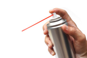 Closeup of a hand holding a lubrication spray can.
