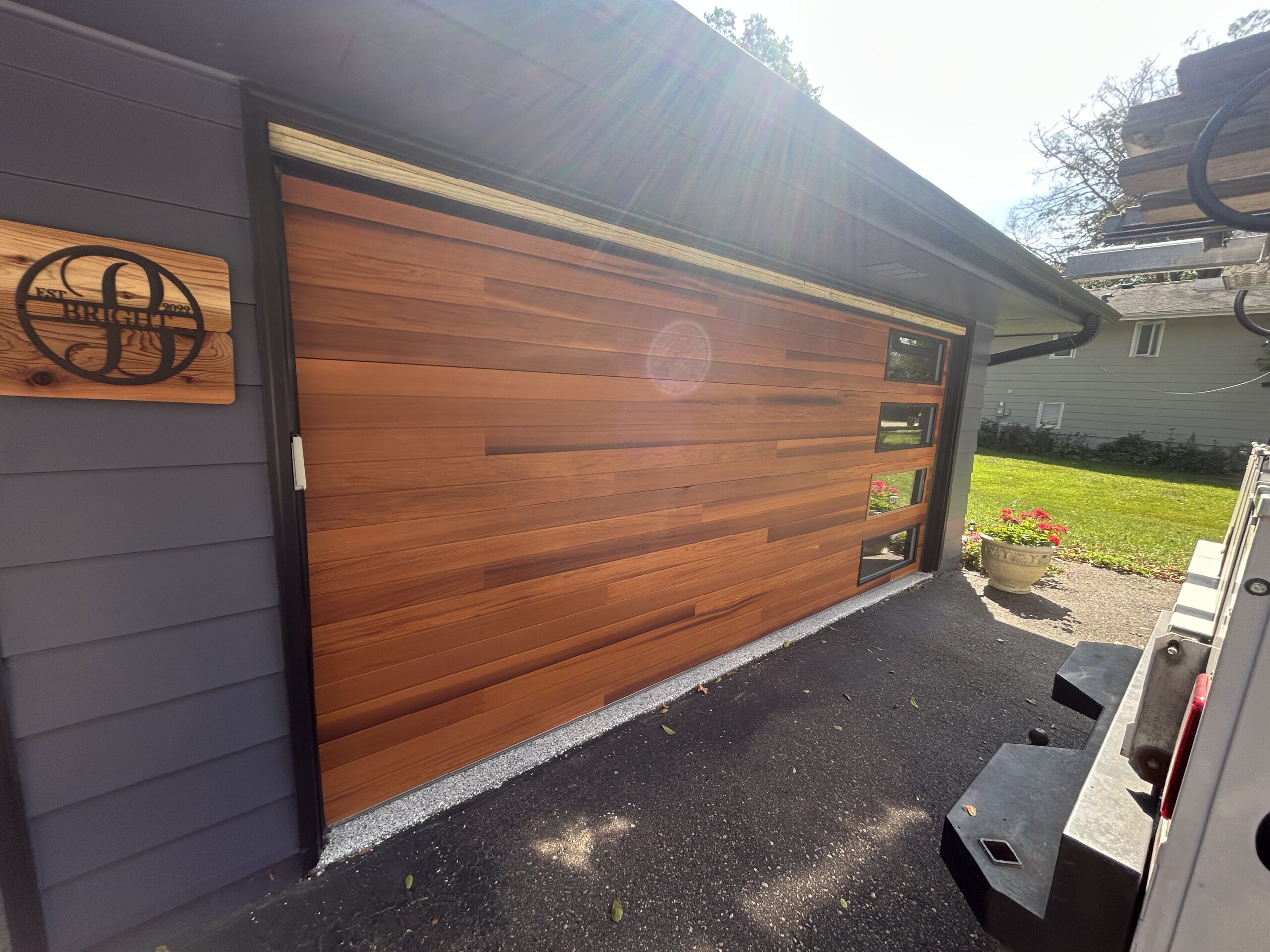 Cedar plank double garage door with windows arranged vertically along the right side.