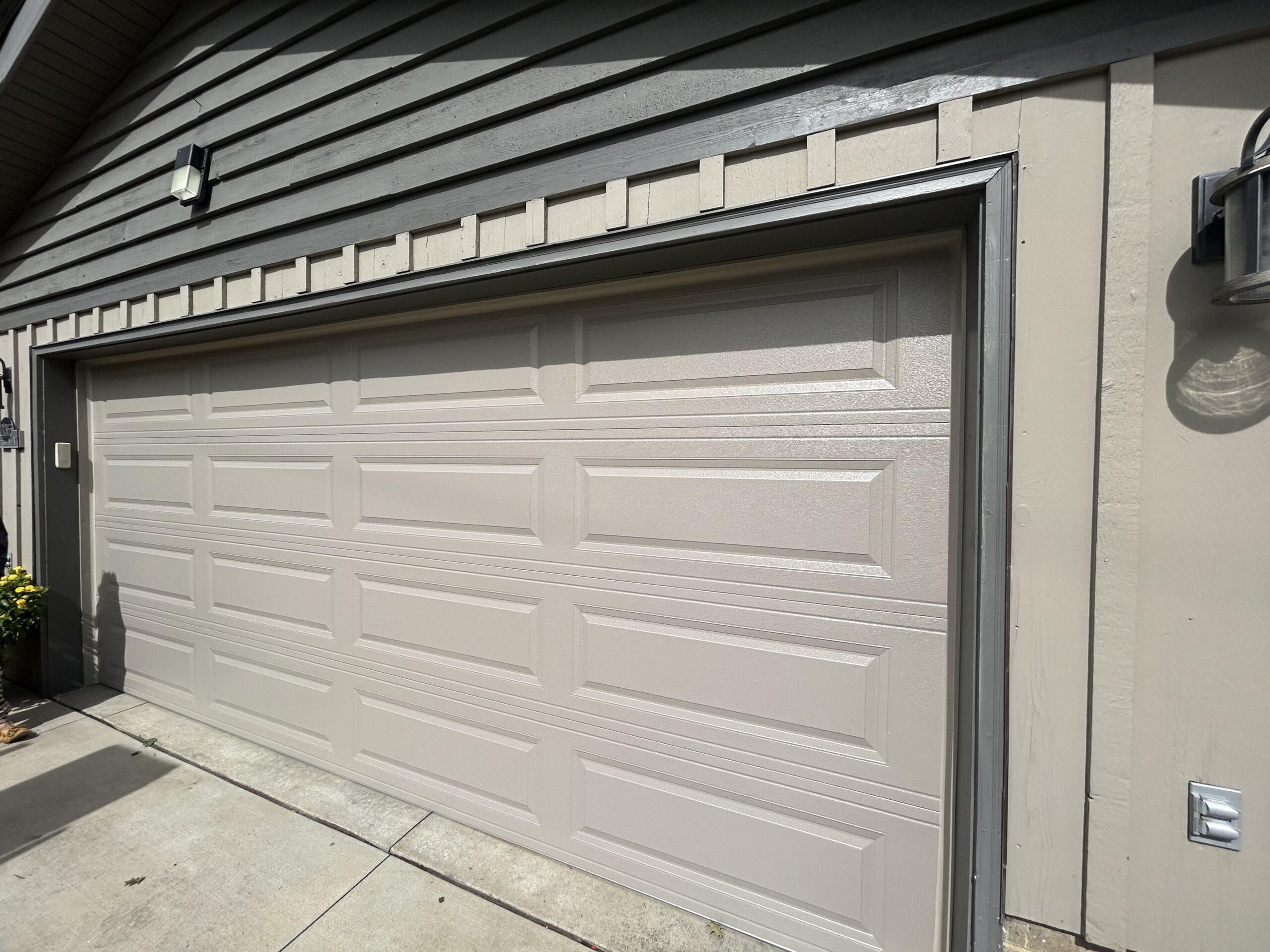 Cedar plank double garage door with windows arranged vertically along the right side.