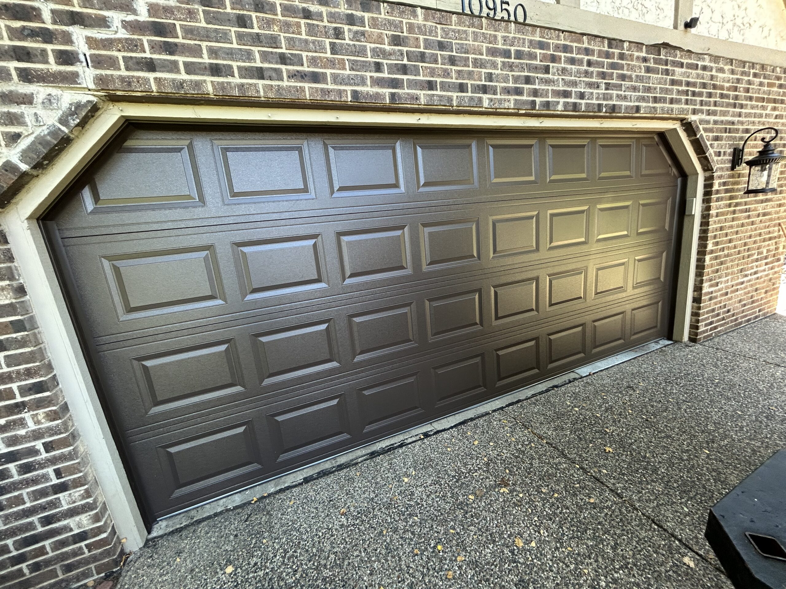 Brown double garage door with short rectangular panels and no windows.